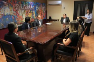 Un grupo de personas integrantes de Uno a Uno y de UAdeO charlando sentados en una mesa.